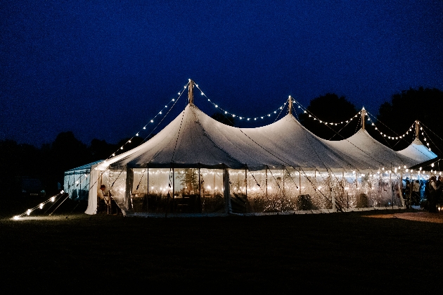 marquee with clear sides decorated with festoon lighting by night