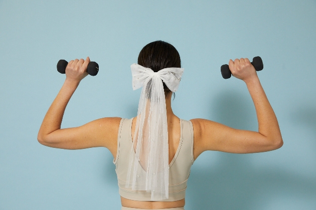 Woman working out with weights waring a bow and veil in her hair