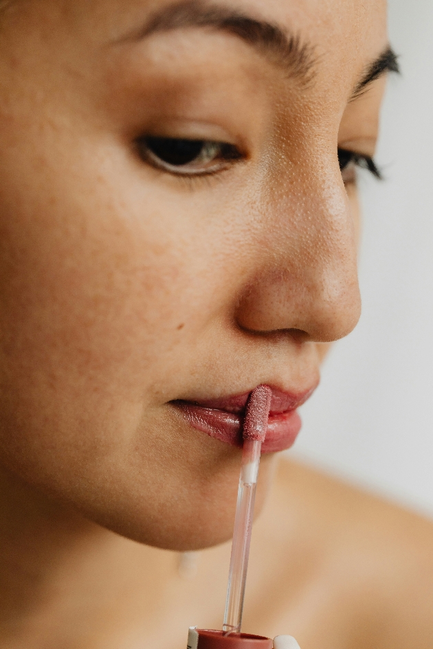 Close up of woman applying soft pink lipgloss