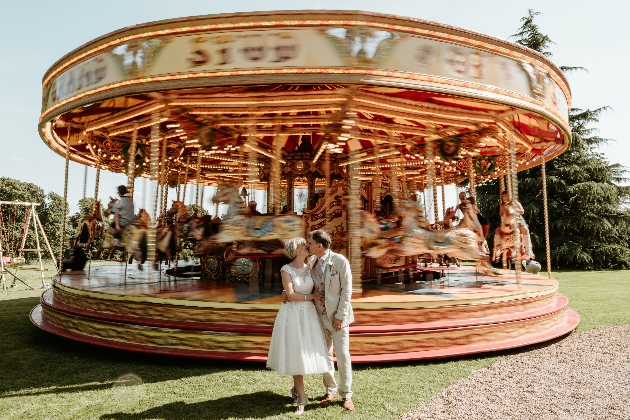 Couple kissing in front of a moving carousel